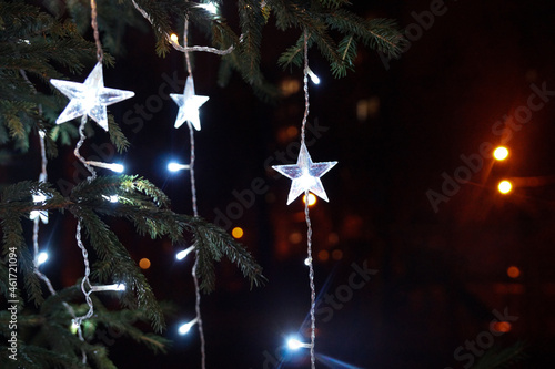 White lights on the Christmas tree. Star shaped decoration. Bright Christmas Eve in dark night.