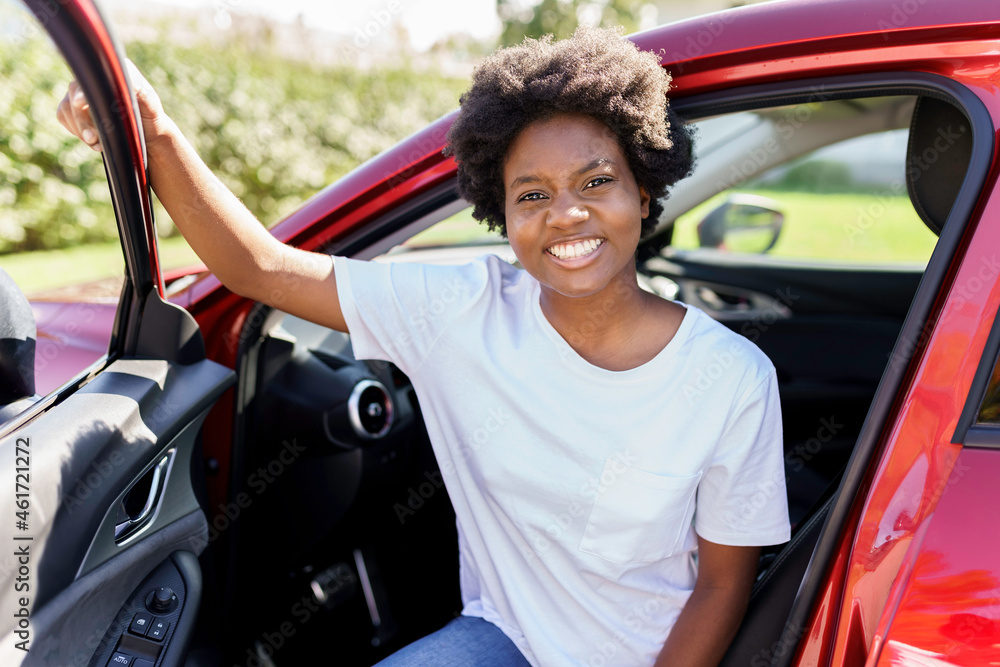 Young black woman sit on is first red car
