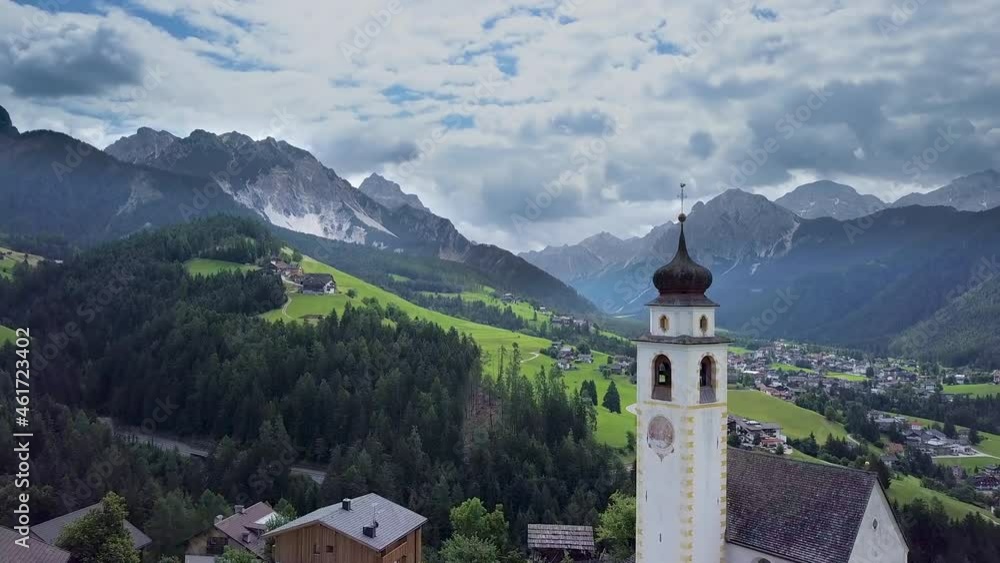 Aerial flight over the bell tower of a church in the Dolomites