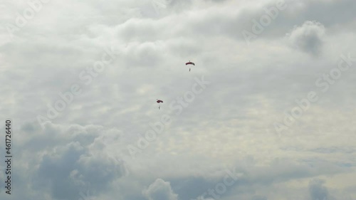 two single Skydivers with open Parachutes slowely glide down to earth. The scene is in the Netherlands on the Island of Texel during the summer. photo