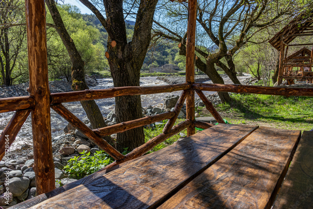 View from a wooden gazebo with a table to the mountain river and mountains.