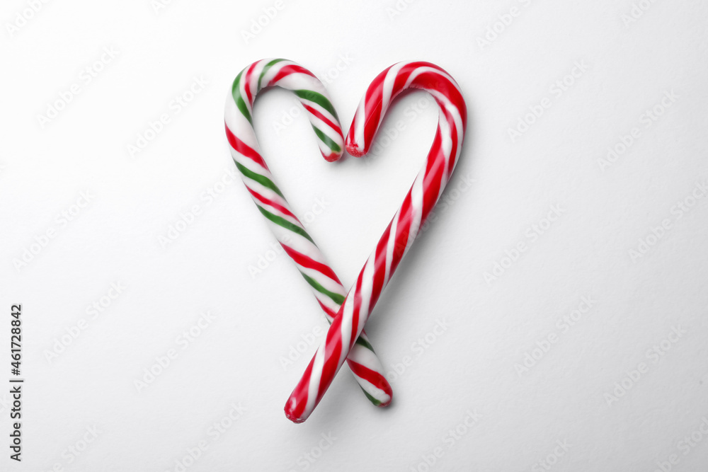 Heart made of sweet Christmas candy canes on white background, top view