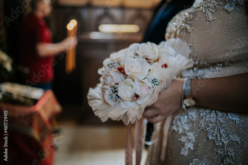 Shallow focus of a bride holding a bouquet of flowers during a wedding cerem photo