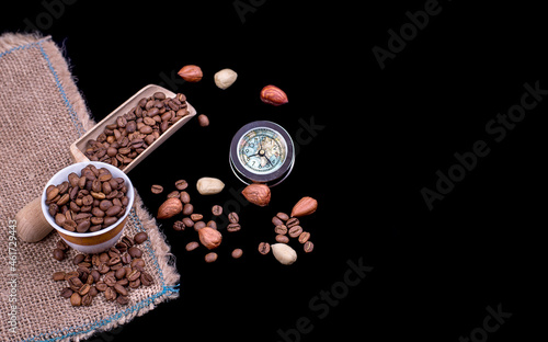 Coffee beans, vintage watch and ceramic cup on black background. Top view.