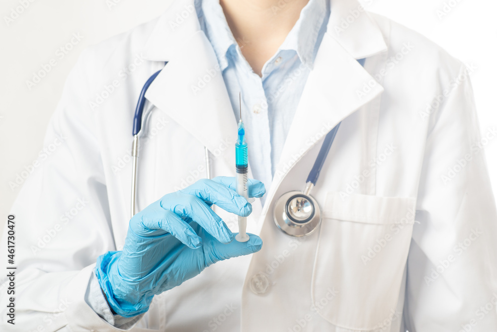 A woman doctor holds a syringe in front of the ward A woman doctor holds a syringe in front of the ward