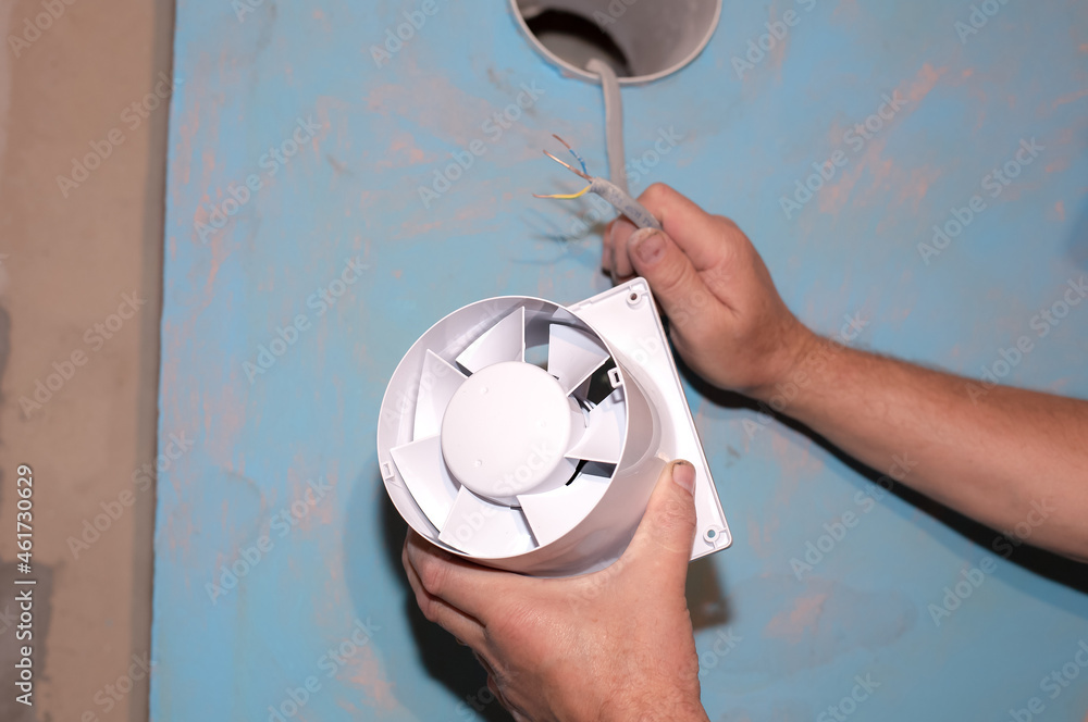 Man is installing the wall bathroom fan vent. Restoration process ...