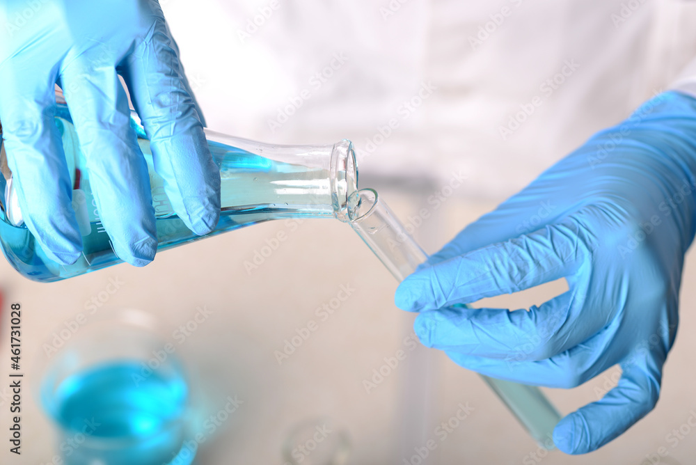 Laboratory beaker in analyst's hand in plastic glove Laboratory beaker in analyst's hand in plastic glove