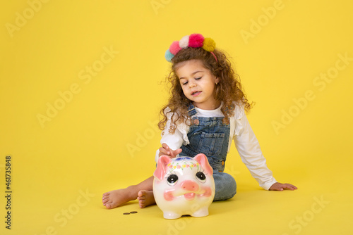 Cute little Cute little girl with piggy bank , yellow backgroundgirl with piggy bank , yellow background photo