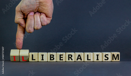 Illiberalism or liberalism symbol. Businessman turns cubes and changes the word 'illiberalism' to 'liberalism'. Beautiful grey background. Business, illiberalism or liberalism concept. Copy space.