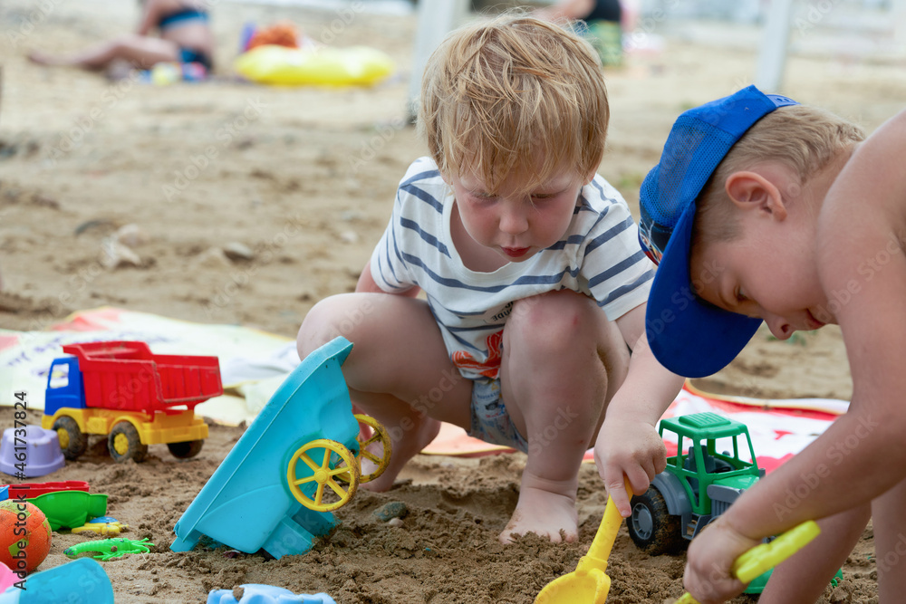 Two children play in the sand with plastic toys Two children play in the sand with plastic toys