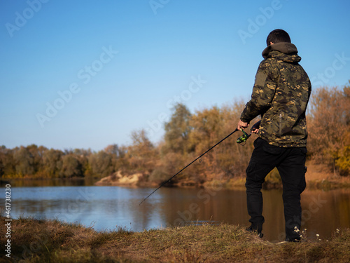 A young man is a fisherman with a spinning rod. Autumn fishing, outdoor activities and hobbies