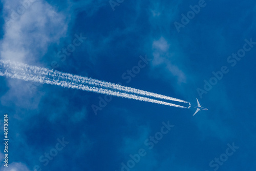 Cargo plane in the sky at the echelon. light clouds and blue sky, condensation trail behind the aircraft
