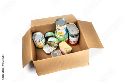 A grocery store checkout cardboard box filled with a variety of fake generic labelled food cans isolated on white