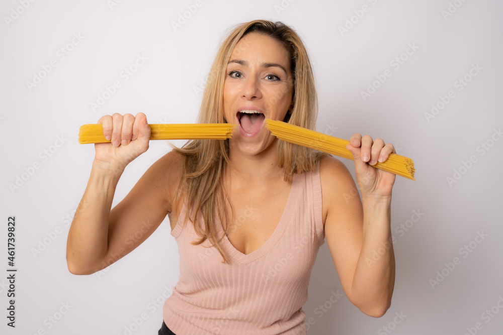 Photo of pretty funny young woman wearing casual clothing holding pasta isolated white background Photo of pretty funny young woman wearing casual clothing holding pasta isolated white background