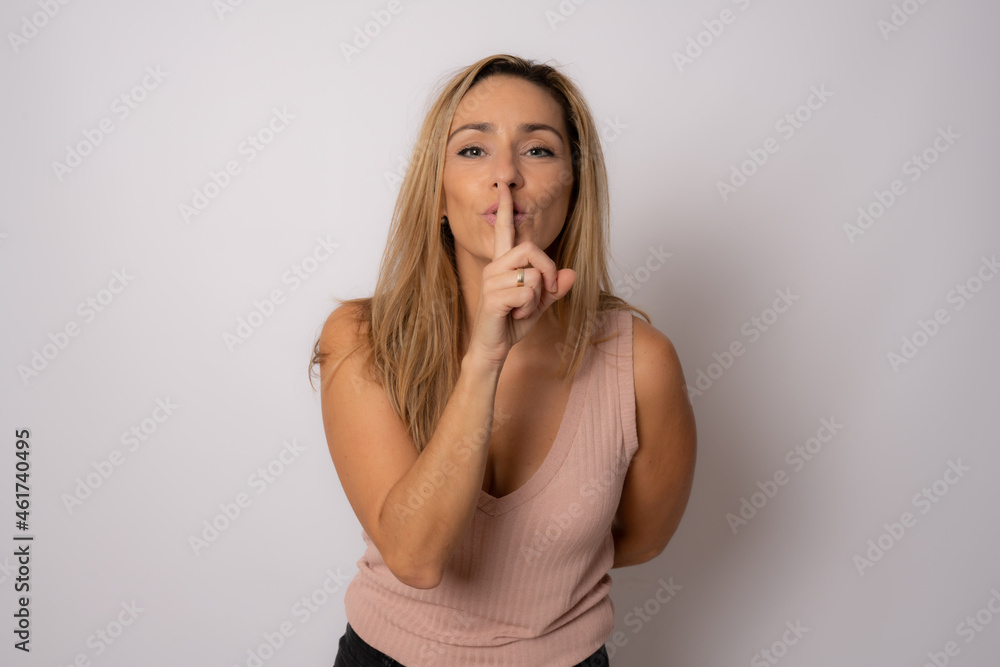 Woman smiling and making quiet sign isolated over white background. Woman smiling and making quiet sign isolated over white background.