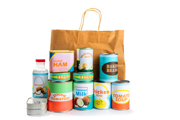 A paper grocery store shopping bag with a variety of fake generic labelled food cans isolated on white 
