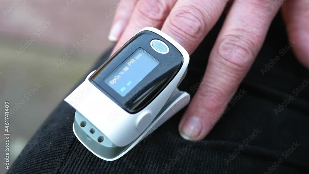 Women's hands measure oxygen levels using a pulse oximeter. A pulse