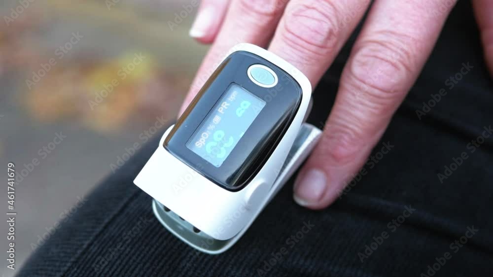 Women's hands measure oxygen levels using a pulse oximeter. A pulse