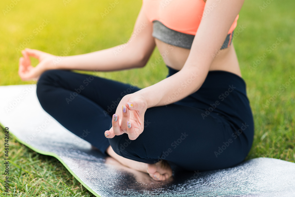 Caucasian girl practicing yoga while sitting on a mat in the lotus position