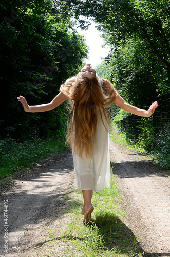 junge schöne Frau tanzt im Sommerlicht auf Waldweg