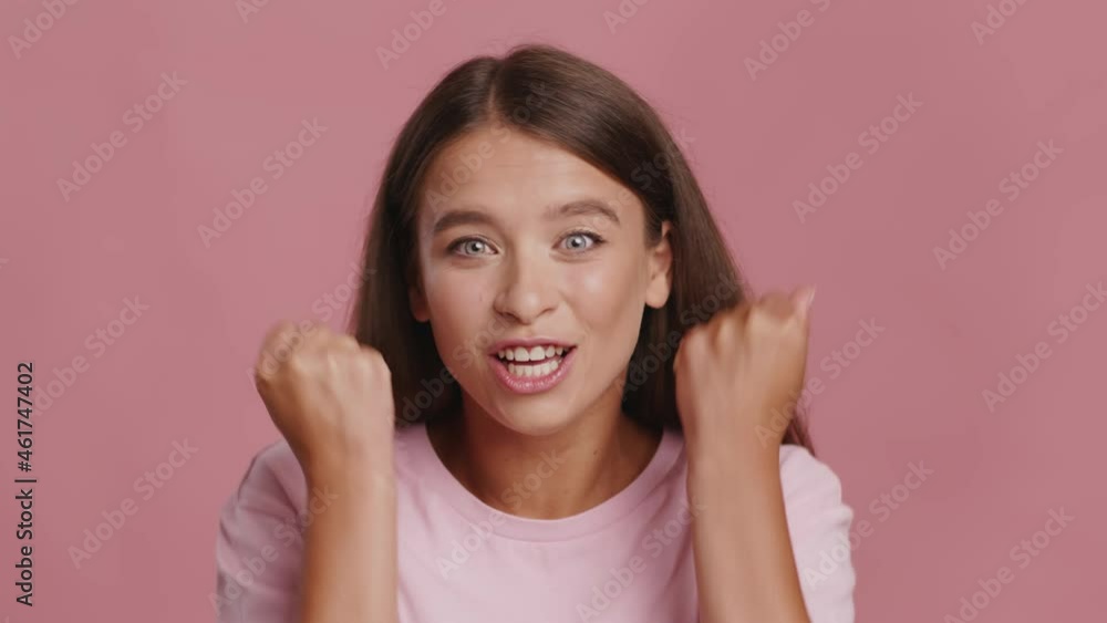 Joyful Woman Shaking Fists Celebrating Success Over Pink Background Joyful Woman Shaking Fists Celebrating Success Over Pink Background