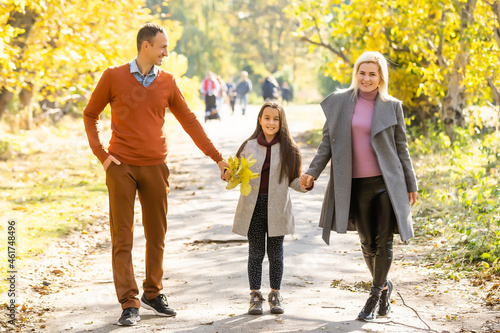 Young happy family while walking in the autumn park.