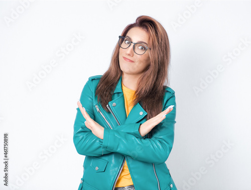 Limit. Woman gesturing stop or x sign with her arms, refuses or reject something, girl crossing her hands, wearing green leather jacket, isolated on white background