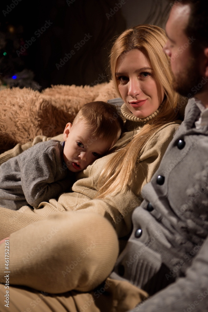 A young family is resting on the couch on a cold winter evening. A young family is resting on the couch on a cold winter evening.