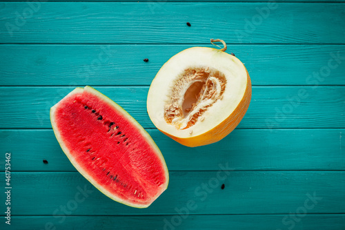 Watermelon and ripe melon sliced in a half with a backsword on the wooden turquoise background. Red juicy summer fruit berry photo