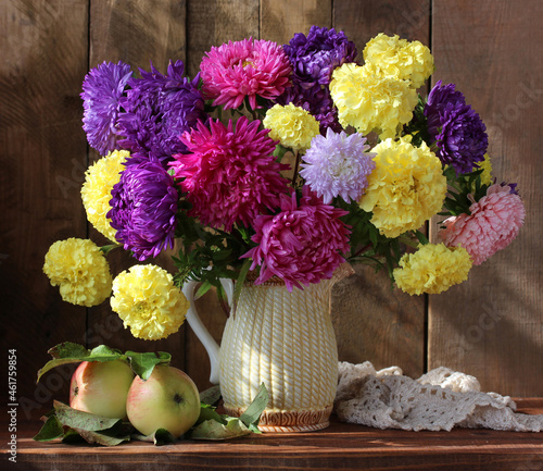 bouquet of asters in a jug and apples