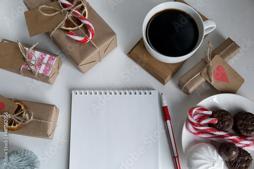 Notepad, coffee, christmas gifts, sweets on a light background
