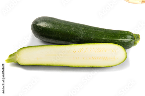 a whole green zucchini squash and a cut up zucchini showing the seeds isolated on white