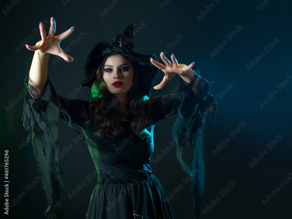 A witch creates magic, a young beautiful brunette in a pointed hat