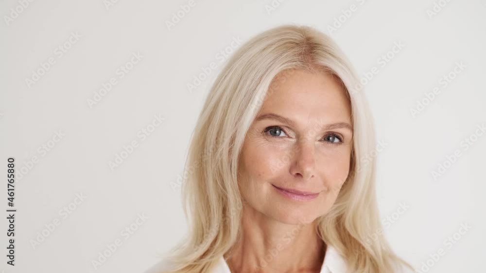 Close-up view of the confident mature woman looking at the camera in the white studio Close-up view of the confident mature woman looking at the camera in the white studio