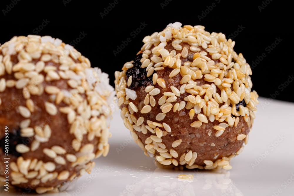 Beautiful candies with sesame seeds on a white plate on a black background Beautiful candies with sesame seeds on a white plate on a black background
