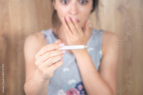 surprised and sad woman holding thermometer