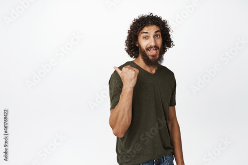 Handsome hispanic man pointing left, showing interesting proposal, sale offer, standing in casual t-shirt over white background