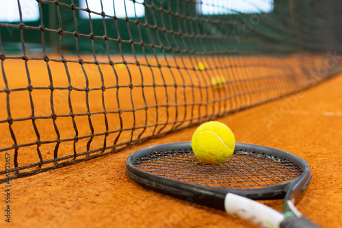Close up tennis ball, racket and net on court. Close up of tennis ball on clay court. Red clay court.