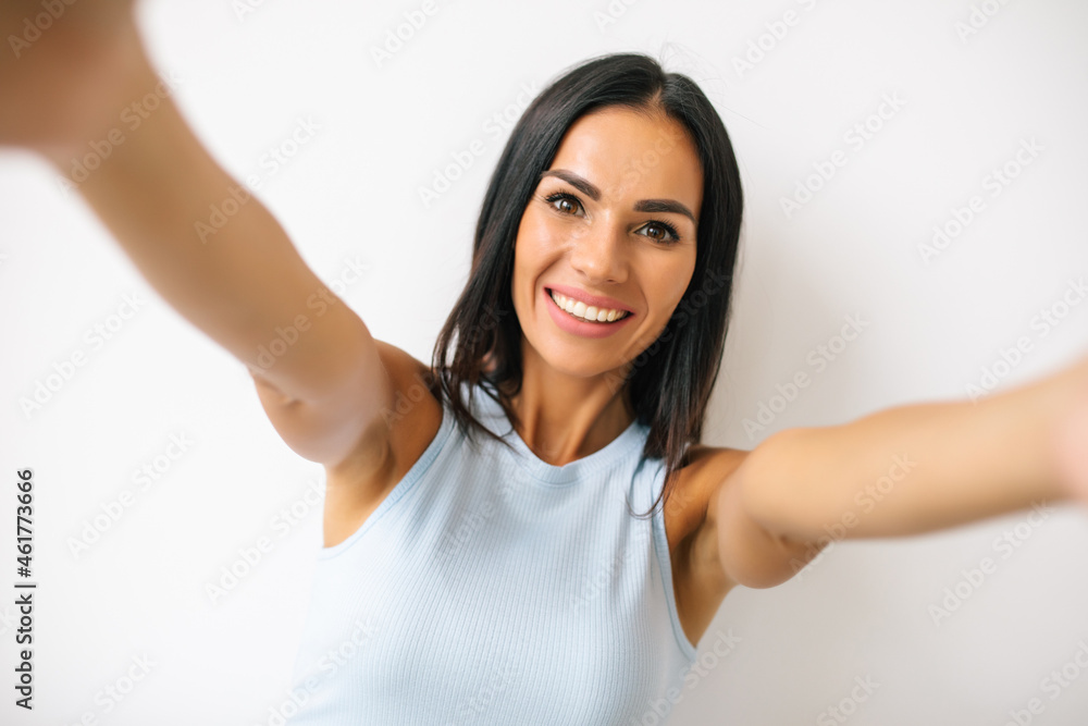 Portrait of a happy young woman making funny face while taking pictures of herself over white background Portrait of a happy young woman making funny face while taking pictures of herself over white background