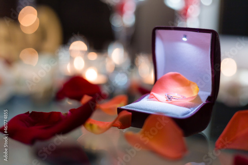 Gold ring, wedding ring in red box and, red heart on white-red background with beautiful bokeh. The moment of a wedding, anniversary, engagement, or Valentine's Day. Happy day.