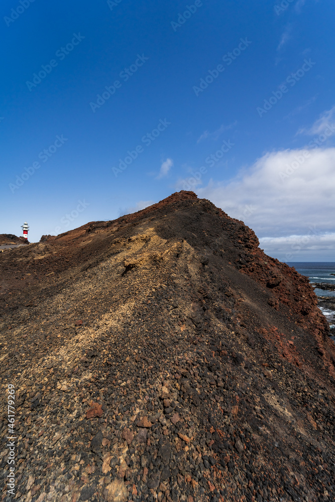 Rocky coast of the Atlantic Ocean at Cape Teno. A lighthouse in the background. Tenerife. Canary Islands. Spain.