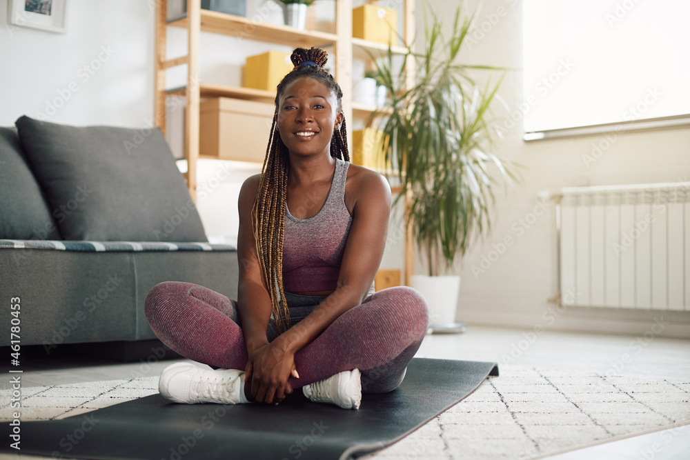 Happy African American athletic woman relaxes on exercise mat during home workout. Happy African American athletic woman relaxes on exercise mat during home workout.