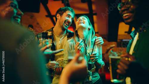 Carefree couple laughs while being on party in pub at night.
