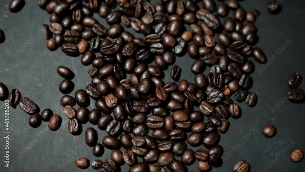 Bunch of roasted coffee beans being poured onto black surface Bunch of roasted coffee beans being poured onto black surface