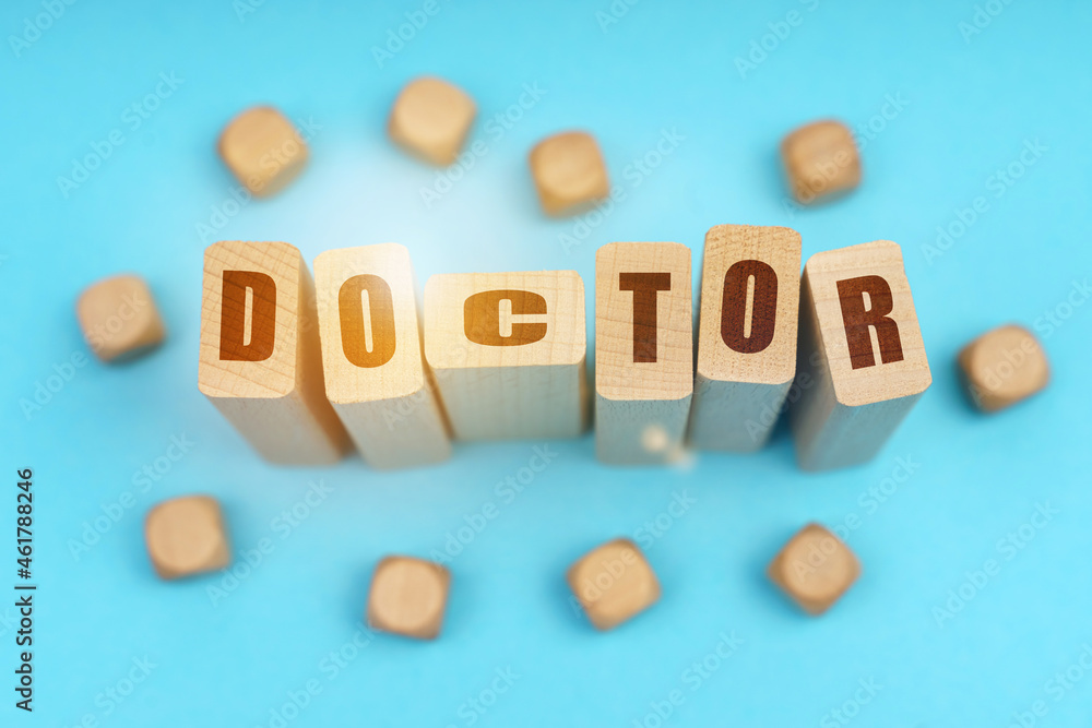 On a blue background, wooden cubes and Jenga with the inscription - DOCTOR On a blue background, wooden cubes and Jenga with the inscription - DOCTOR
