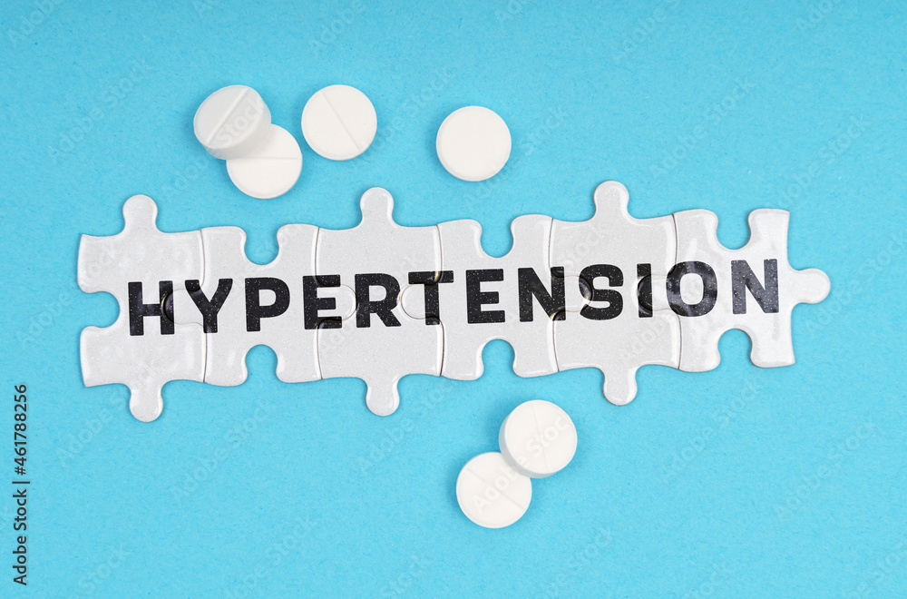 On a blue background pills and puzzles with the inscription - HYPERTENSION On a blue background pills and puzzles with the inscription - HYPERTENSION