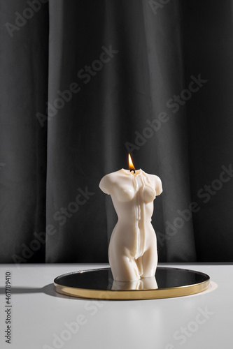 Candle in woman torso shape burning in grey modern interior room, atmosphere and smoke after candle