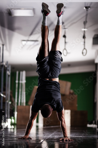 Muscular athlete standing and walking on hands upside down photo