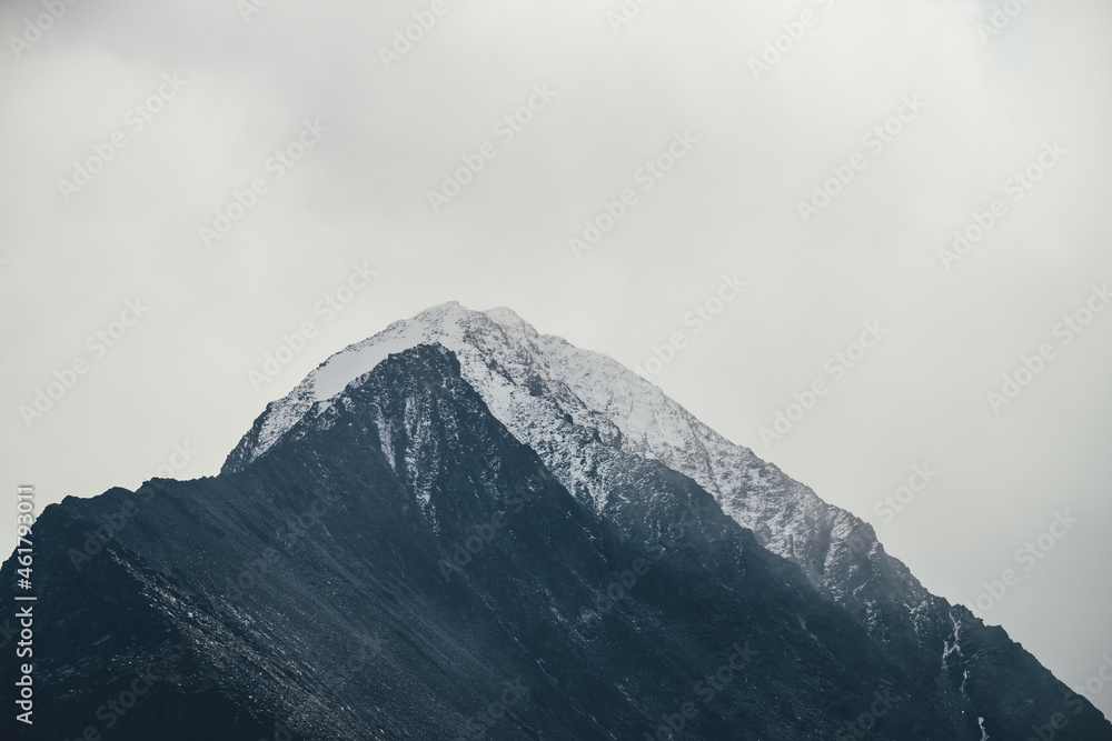Dark atmospheric landscape with high black rocky mountain top with snow in cloudy sky. Dramatic mountain landscape with snow peaked top in haze in overcast weather. Gloomy view to awesome rocks in fog Dark atmospheric landscape with high black rocky mountain top with snow in cloudy sky. Dramatic mountain landscape with snow peaked top in haze in overcast weather. Gloomy view to awesome rocks in fog