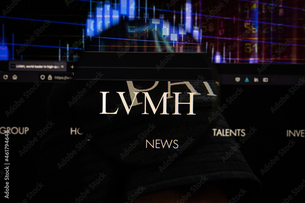 LVMH company logo on a website with blurry stock market developments in the  background, seen on a computer screen through a magnifying glass Stock  Photo